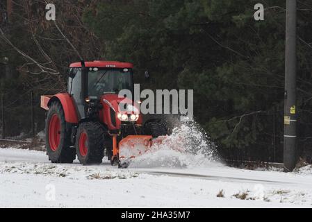 Pultusk, Polen - 10. Dezember 2021: Schneeräumung von einer Landstraße mit einem Traktor mit Schneepflug. Stockfoto