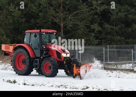 Pultusk, Polen - 10. Dezember 2021: Schneeräumung von einer Landstraße mit einem Traktor mit Schneepflug. Stockfoto