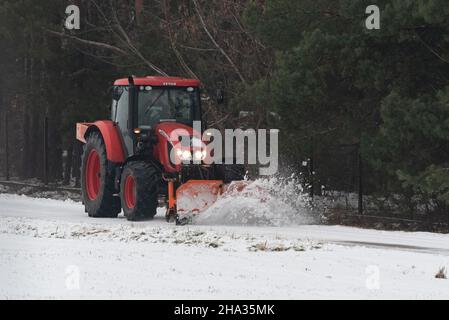 Pultusk, Polen - 10. Dezember 2021: Schneeräumung von einer Landstraße mit einem Traktor mit Schneepflug. Stockfoto