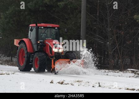 Pultusk, Polen - 10. Dezember 2021: Schneeräumung von einer Landstraße mit einem Traktor mit Schneepflug. Stockfoto