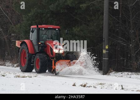 Pultusk, Polen - 10. Dezember 2021: Schneeräumung von einer Landstraße mit einem Traktor mit Schneepflug. Stockfoto