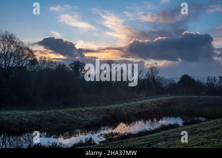 Sonnenuntergang über einem Regenwasserteich neben einem neuen Wohnbaugebiet, Oaklands Park, Ashbourne, Derbyshire Stockfoto