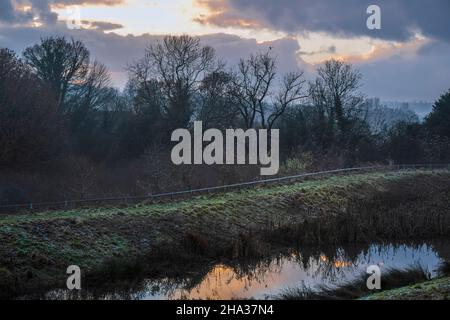 Sonnenuntergang über einem Regenwasserteich neben einem neuen Wohnbaugebiet, Oaklands Park, Ashbourne, Derbyshire Stockfoto