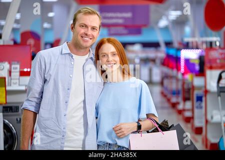 Porträt eines lächelnden fröhlichen Paares nach dem Einkaufen, Blick auf die Kamera, posiert, kaukasischen Mann und Frau lässig in hellen Kleidern gekleidet. Einkaufen, c Stockfoto