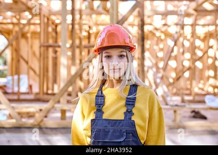 Porträt der jungen kaukasischen Baumeister Architektin Frau in Hardhat posiert gegen neue Wohnbau Haus Rahmung, an sonnigen Tag im Freien, dresse Stockfoto