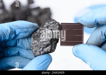 Kohle neben Solarpanel in wissenschaftlichen Händen im Labor. Forschung im Bereich der grünen Energiewende. Stockfoto