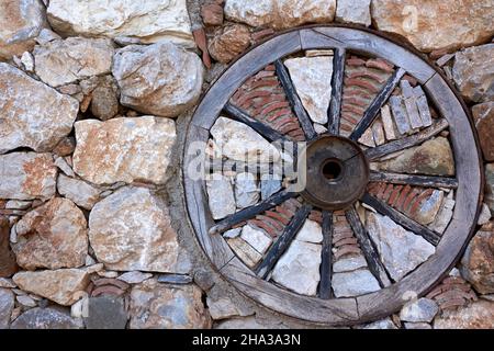 Holzrad im alten Stil in der Steinmauer Stockfoto