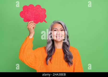 Foto von niedlichen grauen Frisur ältere Dame sprechen tragen orange Pullover isoliert auf grünem Hintergrund Stockfoto