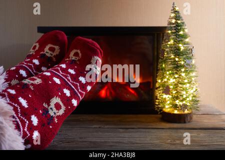Nahaufnahme einer Frau Beine mit Socken Fußrasten in einem Kamin im Winter Stockfoto