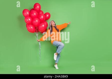 Ganzkörper-Foto von reifen Frau halten viele Helium Kugeln valentinstag Geschenk Dekor isoliert über grüne Farbe Hintergrund Stockfoto