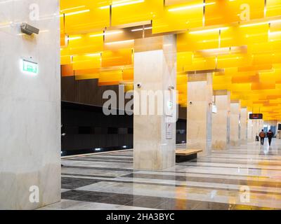 8. Dezember 2021. Moskau. Russland. Säulen und anmutige orangefarbene Deckenleuchten im Inneren der neuen U-Bahn-Station Novatorskaya auf dem Abschnitt der großen Kreislinie der Moskauer Metro. Stockfoto