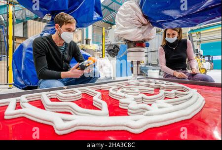 10. Dezember 2021, Sachsen, Chemnitz: Sandra Gelbrich, Leiterin des Forschungsbereichs "Leichtbau im Bauingenieurwesen" an der TU Chemnitz, und Arbeitsgruppenleiter Enrico Rudolph verfolgen die Herstellung eines Betonschwungbogens im automatisierten 3D-Druckverfahren. Seit fünf Jahren forschen die Wissenschaftler am Institut für Leichtbau der Technischen Universität Chemnitz an automatisierten additiven Fertigungstechnologien. Vor kurzem präsentierten sie den weltweit ersten 3D-gedruckten Beton-Flying Buttress. In mehreren Lays wird eine spezielle Faserbeton-Formel angewendet Stockfoto