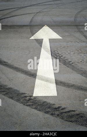 Weißer Pfeil auf einem leeren Parkplatz auf Asphalt Stockfoto