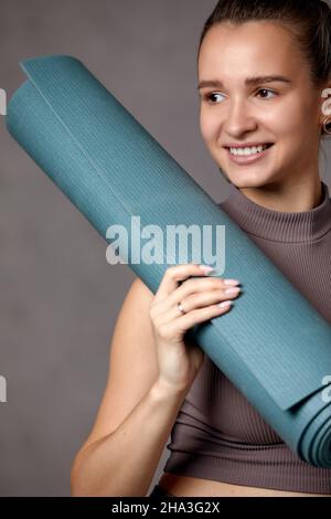 Lächelnde Schwangere in Sportkleidung bereit für Morgengymnastik oder Bewegung. Glückliche junge Frau folgen gesunden Lebensstil während der Schwangerschaft, halten Yoga Stockfoto