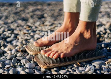 Nahaufnahme der weiblichen Füße auf Brettern mit Nägeln. Stockfoto