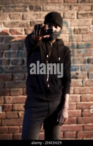Dieb bewaffnete Mann rauben Menschen durch Waffe auf der Straße, Porträt von gefährlichen Kerl mit Waffe auf die Kamera. Aggressive kriminellen Hooligan mit Waffe Einbrecher. Crimina Stockfoto