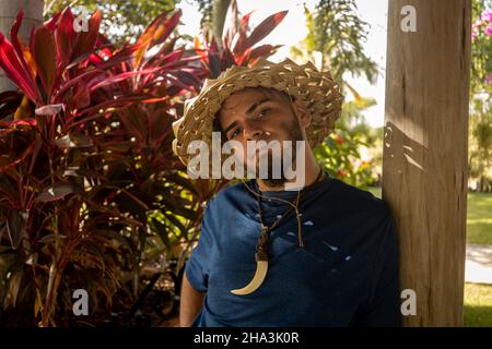 Junge Erwachsene Kaukasische Mann und Hippie-Gärtner schauen unter den Pflanzen. Mann, der seine Arbeit genießt. Stockfoto