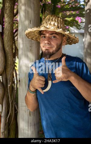 Junge Erwachsene Kaukasische Mann und Hippie-Gärtner schauen unter den Pflanzen. Mann, der seine Arbeit genießt. Stockfoto