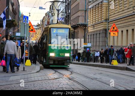 Einkäufer und Reisende in der überfüllten Aleksanterinkatu mit der grünen HSL-Straßenbahn an der Straßenbahnhaltestelle Senaatintori. Helsinki, Finnland. 6. Dezember 2017. Stockfoto