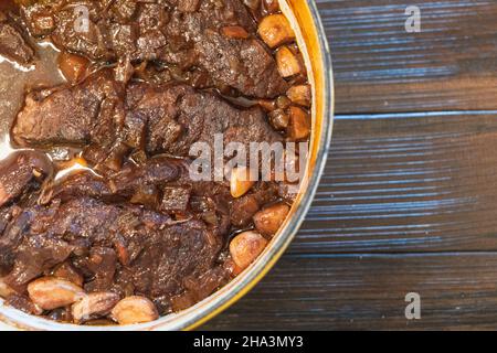 Ein gelber holländischer Ofen mit hausgemachtem geschmortem Rindfleisch, kurzen Rippen in Wein und Knoblauch Stockfoto