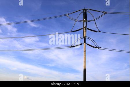 Der Hochspannungsmast, der elektrische Pfosten zeigen mit Hochspannungs-Konstruktion und Stromleitungen, schöner blauer Himmel Hintergrund Stockfoto