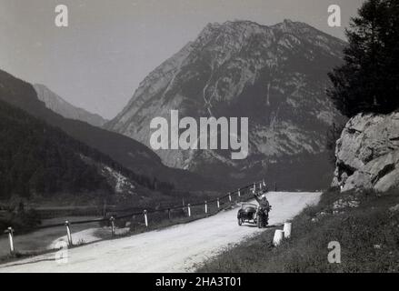 1930s, historisch, auf einer staubigen Bergstraße, eine Dame, die auf einem indischen Scout-Motorike mit Seitenwagen sitzt und der Person in der Ferne winkt, die ihr Foto macht, Alps, Frankreich. Stockfoto