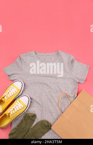 Leeres T-Shirt, Tasche, Sneaker und Socken auf rosa Hintergrund Stockfoto