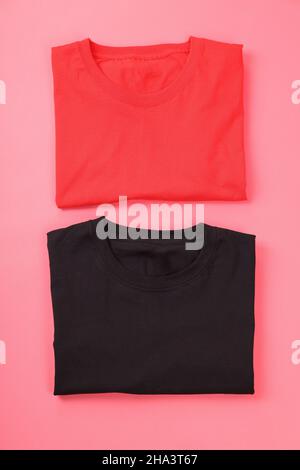 Gefaltete schwarze und rote T-Shirts auf rosa Hintergrund Stockfoto