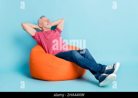 In voller Länge Körpergröße Foto von bärtigen Mann immer Ruhe bei der Arbeit in Sitzsack isoliert pastellblau Hintergrund Stockfoto