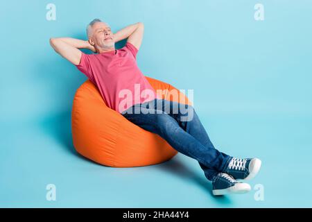 In voller Länge Körpergröße Foto von bärtigen Mann immer Ruhe auf Pause träumen in Sitzsack isoliert pastellblau Hintergrund Stockfoto