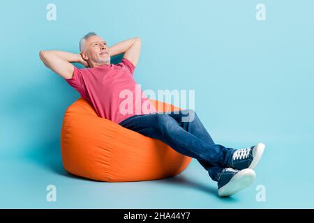 In voller Länge Körpergröße Foto Ältester Mann liegend entspannend auf Sitzsack brechen isoliert pastellblau Farbe Hintergrund Stockfoto