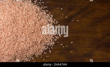 Vollkorn-brauner Reis, gestreut auf einer Holztischplatte, Nahaufnahme von oben mit Platz für Text, Hintergrund des Essens Stockfoto