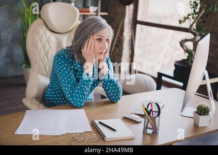 Foto von unglücklich müde verärgert alte Frau Geschäft Dame aussehen pc sitzen Schreibtisch schlechte Laune drinnen im Büro Arbeitsplatz Stockfoto