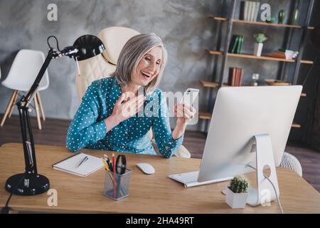 Foto von fröhlich fröhlich fröhlich glücklich grauhaarige alte Dame lächeln Telefon im Büro Arbeitsplatz Arbeitsplatz Arbeitsplatz suchen Stockfoto