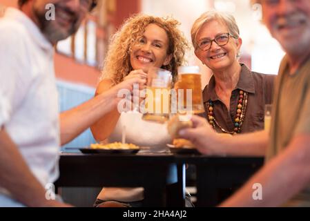 Fröhliche fröhliche Familie mit Spaß und klirrende Biergläser zusammen, während sie am Tisch im Restaurant sitzt. Porträt der Familie beim Toasten von Biergläsern und Feiern im Restaurant Stockfoto