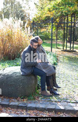 Auf einem weißen Stein sitzend, junge Mann und Frau mit Schilf hinter sich Stockfoto