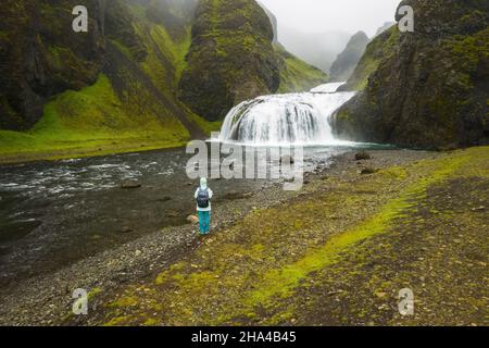 Luftaufnahme der Frau mit Rucksack genießen stjornarfoss Wasserfälle in der Sommersaison. island. Stockfoto