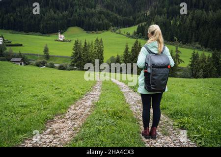 Frau mit Rucksack auf dem Wanderweg zur St. johann Kirche im val di funes Tal, dolomiten, italien, europa. Stockfoto