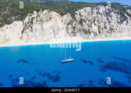 lefkada, griechenland. Abgelegener weißer egremni-Strand mit einsamem Luxus-Yacht-Boot auf der türkisfarbenen Bucht am ionischen Meer. Stockfoto