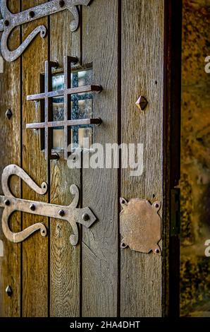 Alte halb offene Holztür eines alten Schlosses, mit rostigen Eisenarbeiten. Stockfoto
