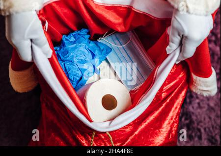 Die Tasche des Weihnachtsmanns voller Toilettenpapier, Gesichtsmasken und Handschuhen Stockfoto