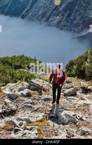 Junger Mann hoch über dem reintal im Reintalanger mit Nebel bedeckt,auf dem Weg zur Knorrhütte 2051m,Aufstieg,zugspitz,wettersteingebirge garmisch-partenkirchen,Loisachtal,oberbayern,bayern,süddeutschland,deutschland,europa, Stockfoto