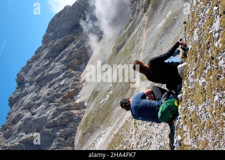 Junges Paar macht eine Pause bei einer Wanderung zur zugspitze 2962 m, im Hintergrund die höllentalspitzen auf dem Jubilumsgrat, wettersteingebirge garmisch-partenkirchen, oberbayern, bayern, süddeutschland, deutschland, europa, Stockfoto