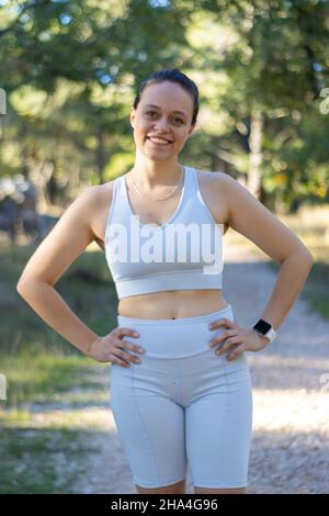 Vertikale Aufnahme einer jungen, sportlichen kaukasischen Frau, die an der Kamera lächelt Stockfoto