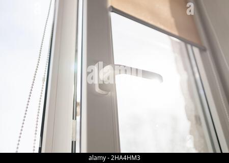 Rollos an den Fenstern, die Sonne dringt nicht in das Haus ein. Modernes weißes Kunststoff-pvc-Fenster mit Waldhintergrund zu Hause, Nahaufnahme. Startseite i Stockfoto