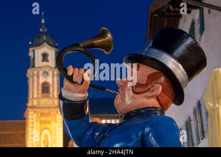 Jagdhornbläser, Eingang zum posthotel, dahinter die Kirche St. peter und paul zur blauen Stunde, obermarkt, mittenwald, oberbayern, bayern, deutschland Stockfoto