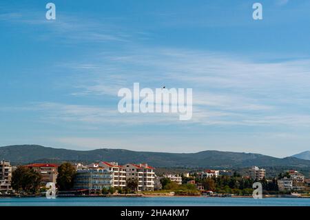 Ein Vogel fliegt über eine kleine Stadt mit Häusern. Im Hintergrund des Bildes. Die Wolken sind schön. Viel Copyspace. Stockfoto