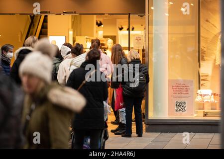 Der Verkäufer überprüft den Impfpass. Am 10. Dezember 2021 gehen Menschen in München einkaufen. Ab Dezember 8 gibt es die Regel von 2G, d.h. man muss gegen das Coronavirus geimpft oder von Covid-19 geborgen werden. (Foto: Alexander Pohl/Sipa USA) Quelle: SIPA USA/Alamy Live News Stockfoto