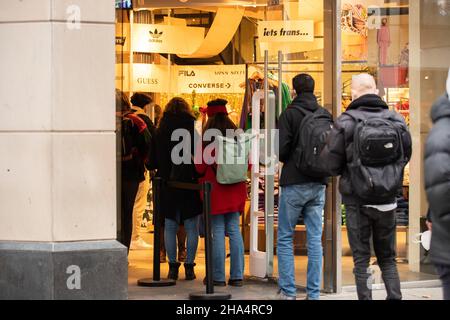 Der Verkäufer überprüft den Impfpass. Am 10. Dezember 2021 gehen Menschen in München einkaufen. Ab Dezember 8 gibt es die Regel von 2G, d.h. man muss gegen das Coronavirus geimpft oder von Covid-19 geborgen werden. (Foto: Alexander Pohl/Sipa USA) Quelle: SIPA USA/Alamy Live News Stockfoto