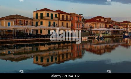 griechenland, griechische Inseln, ionische Inseln, lefkada oder lefkas, lefkada Stadt, Hauptstadt, Morgenlicht, Morgendämmerung, Reihe von Häusern im ersten Morgenlicht, reflektiert im Wasser des Kanals, himmelblau Stockfoto